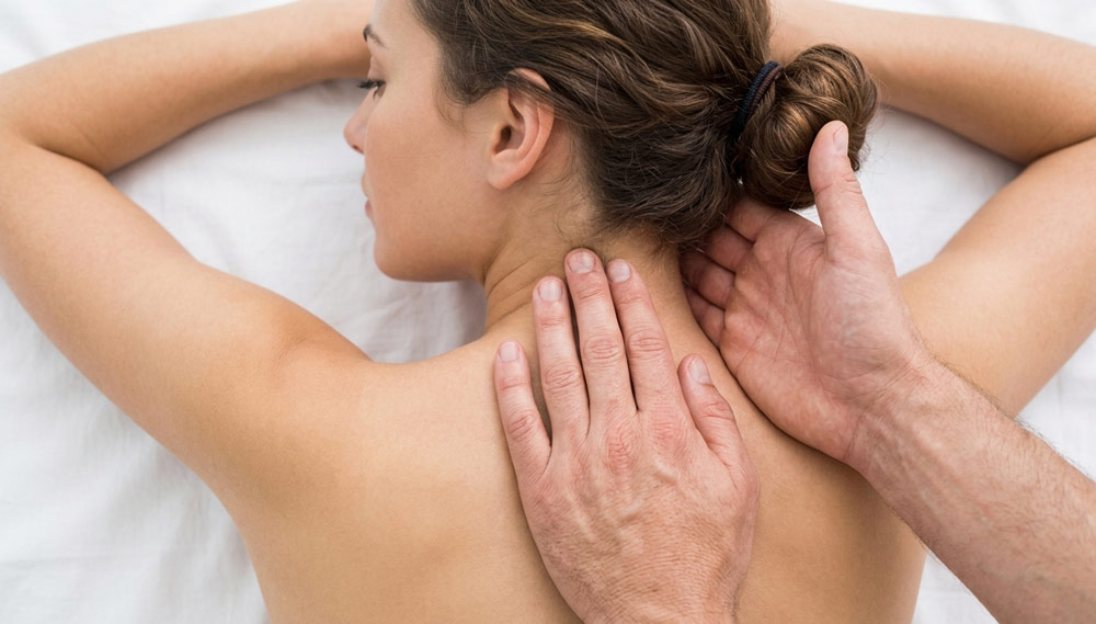 Therapist applying targeted pressure to the neck and upper back to release postural stress and muscle tension during a mobile massage in York.