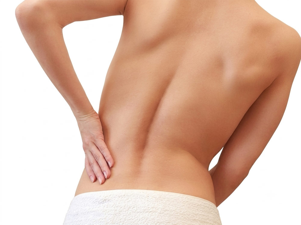 Person experiencing lower back muscle tightness before receiving a mobile sports massage treatment in York.