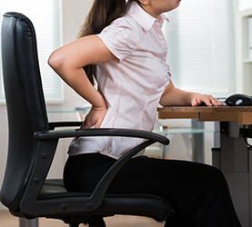 woman sitting with lower back pain from tight muscles 