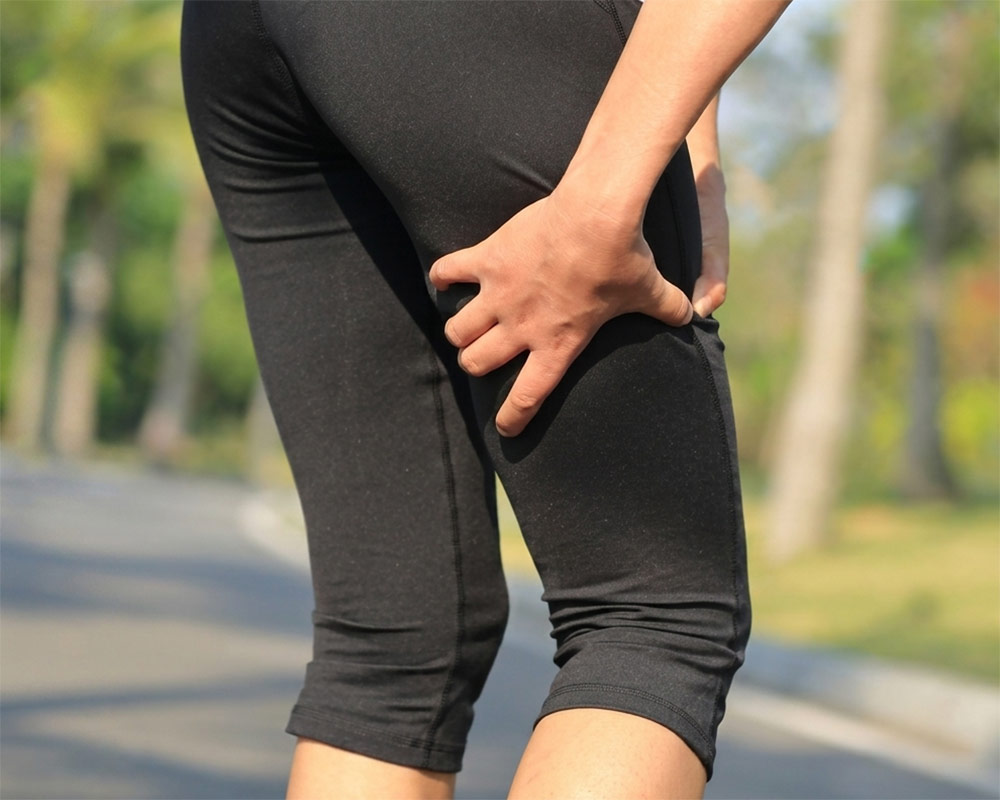 woman with hamstring pain after running A runner clutching the back of their thigh due to a hamstring injury, showing soft-tissue conditions treated by mobile sports massage in York.