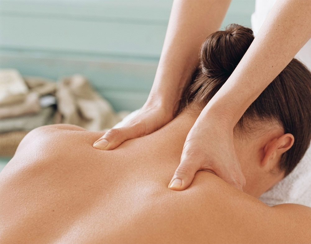 A therapist performing therapeutic remedial neck and shoulder massage to help reduce the frequency and severity of migraines for a client at home in York.
