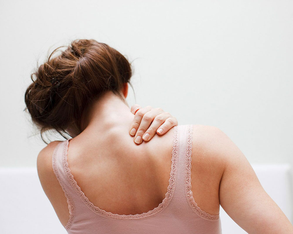 A person clutching a tight, painful neck and shoulder, illustrating the chronic tension often treated with remedial massage in York.
