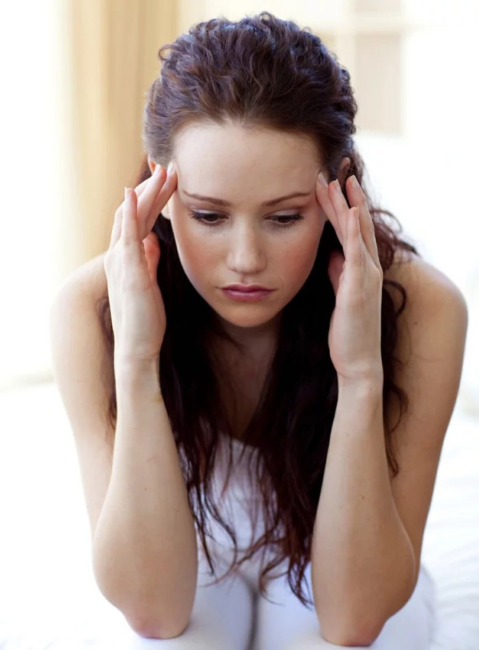 A woman holding her temples in pain, demonstrating tension headache symptoms before receiving a mobile stress relief massage in York.