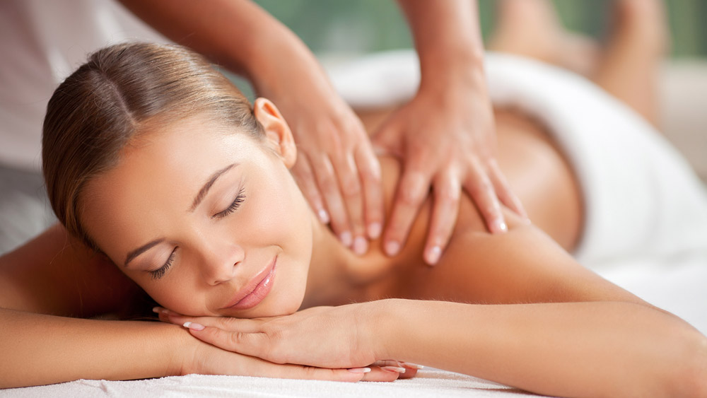 smiling woman having neck massage at home Professional mobile full body massage in York providing restorative shoulder and back tension relief in a home environment.