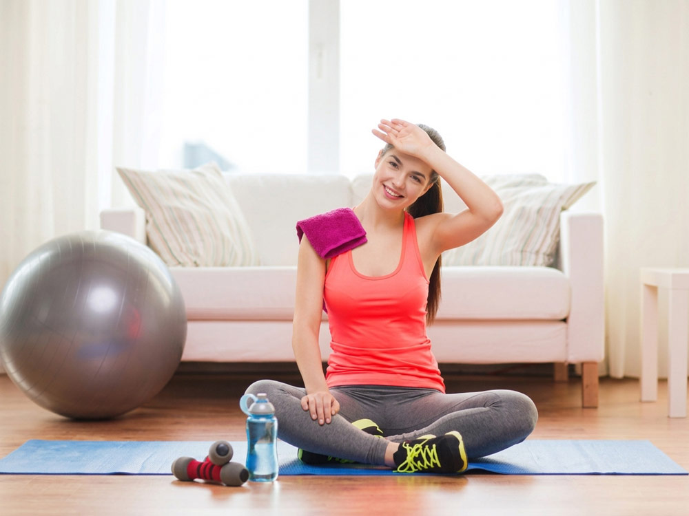 A smiling woman wiping sweat from her forehead after completing a mobile personal training workout at home in York.